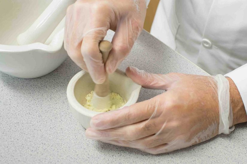 A pharmacist uses a mortar and pestle to compound medication Compounding